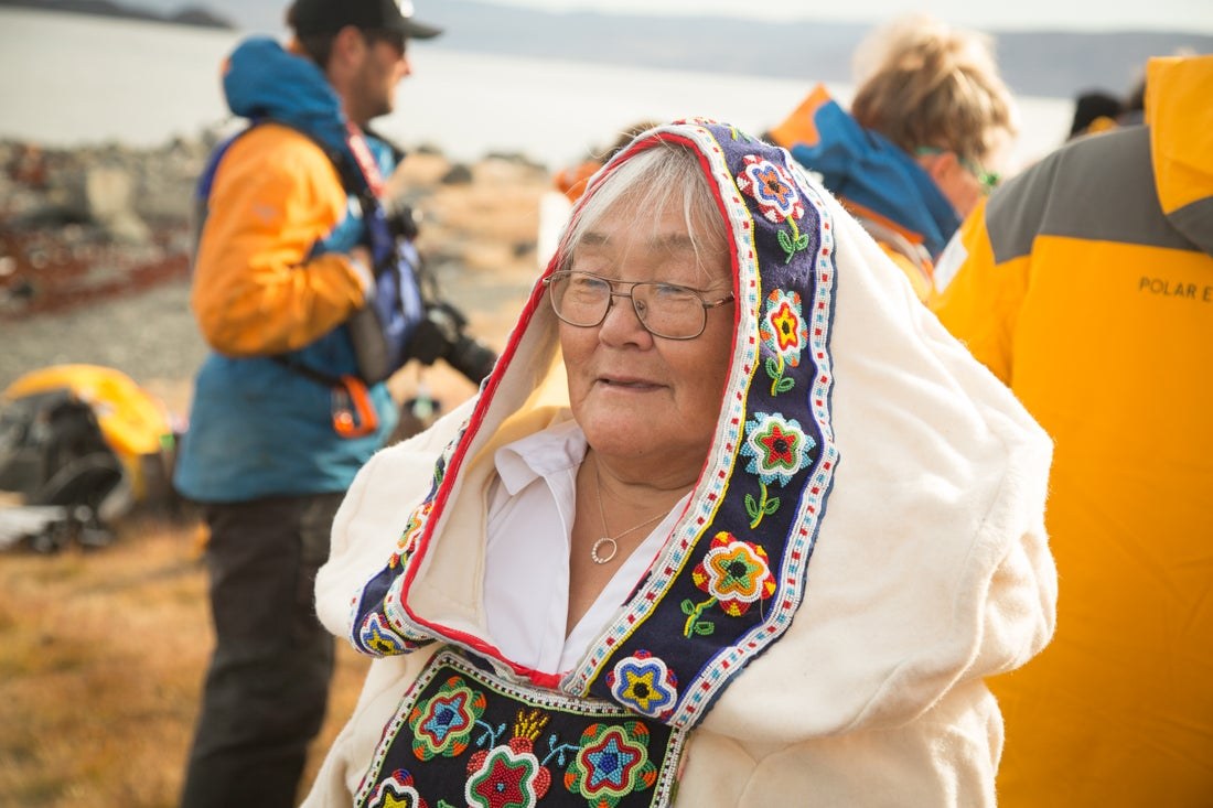 An Inuit elder in a traditional embroidered parka greets expedition guests in Arctic Bay, Nunavut.