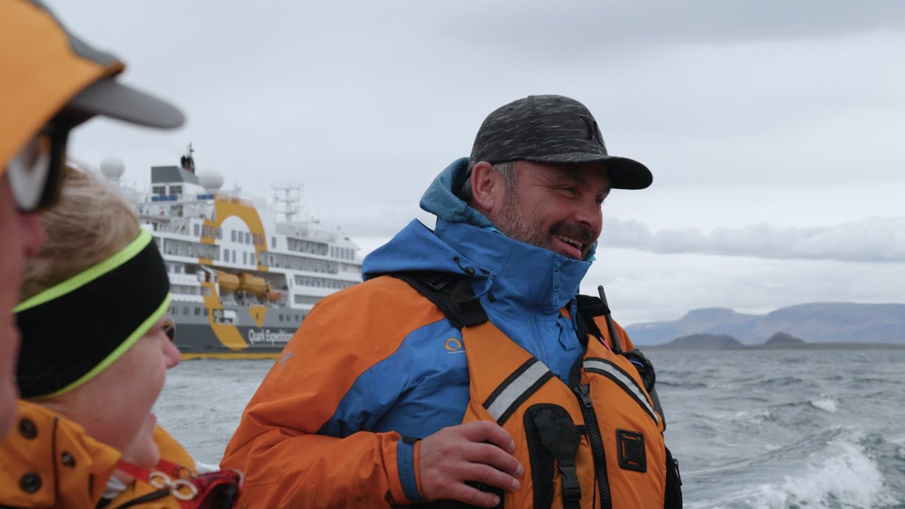 A Quark expedition guide in a Zodiac, with Ultramarine at anchor behind him.
